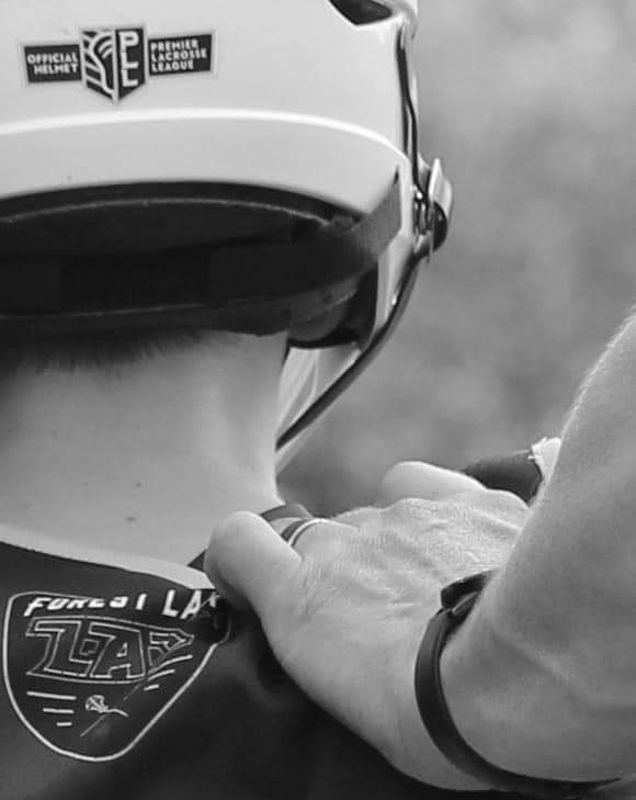 Sean Thomas adjusting a young athlete’s lacrosse helmet