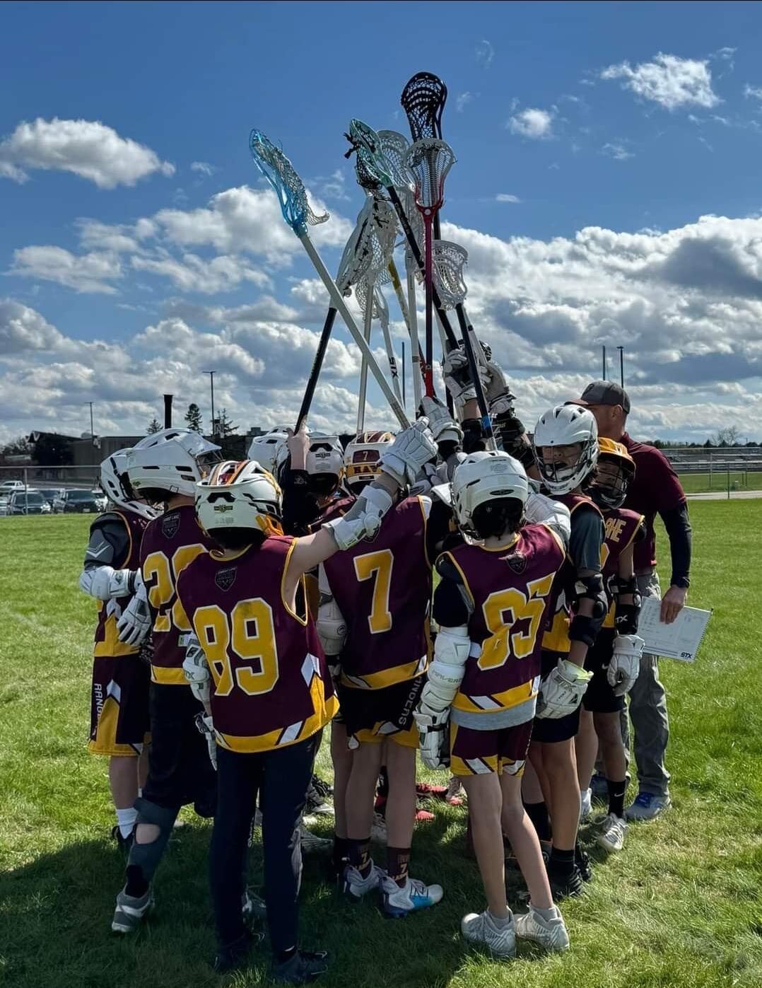 Forest Lake lacrosse team huddle with sticks raised
